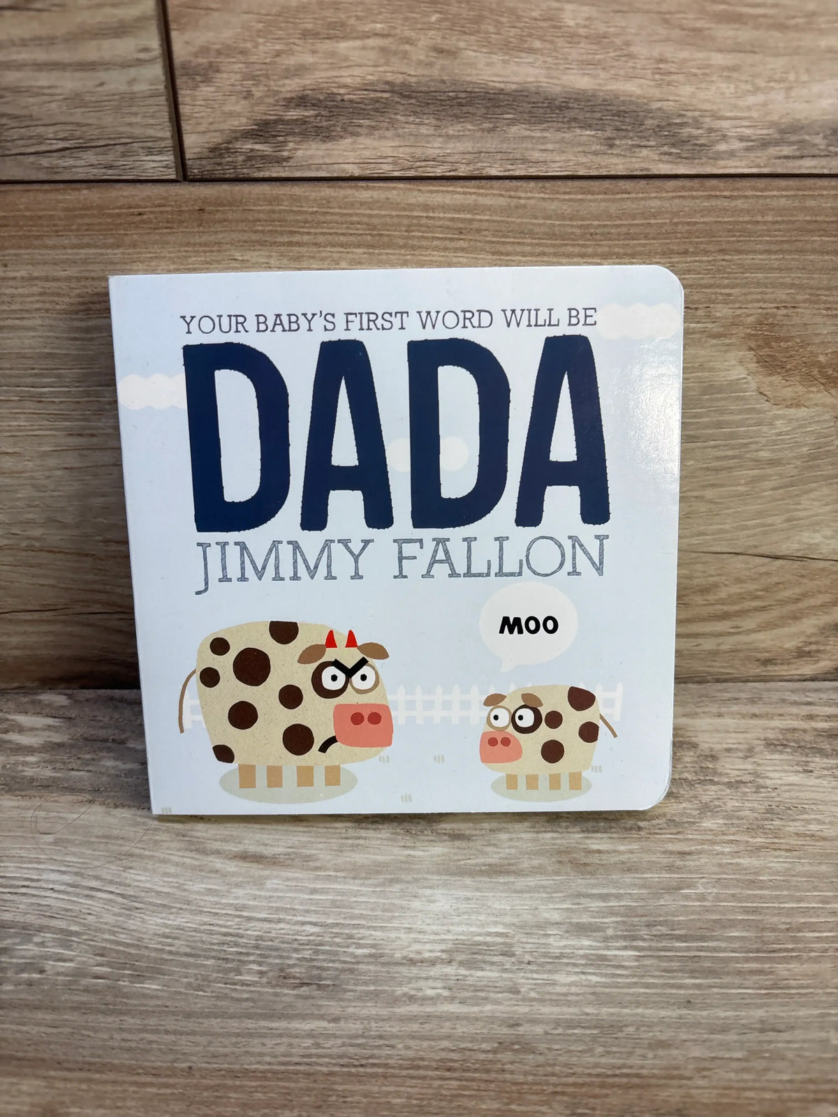 Front view of Your Baby’s First Word Will Be Dada board book by Jimmy Fallon, featuring two cows and MOO text