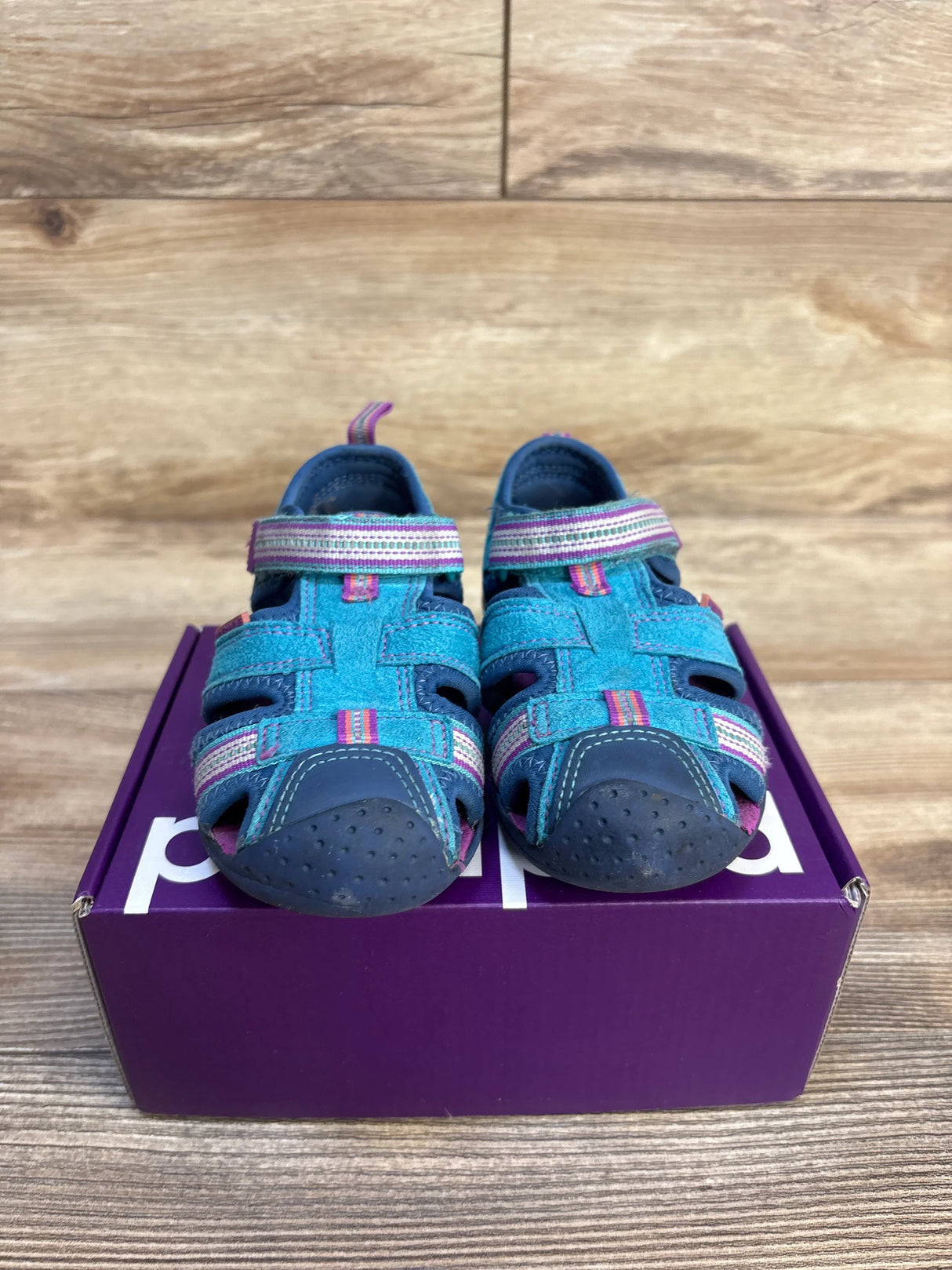 Blue and pink toddler sandals with velcro straps displayed on a purple shoe box