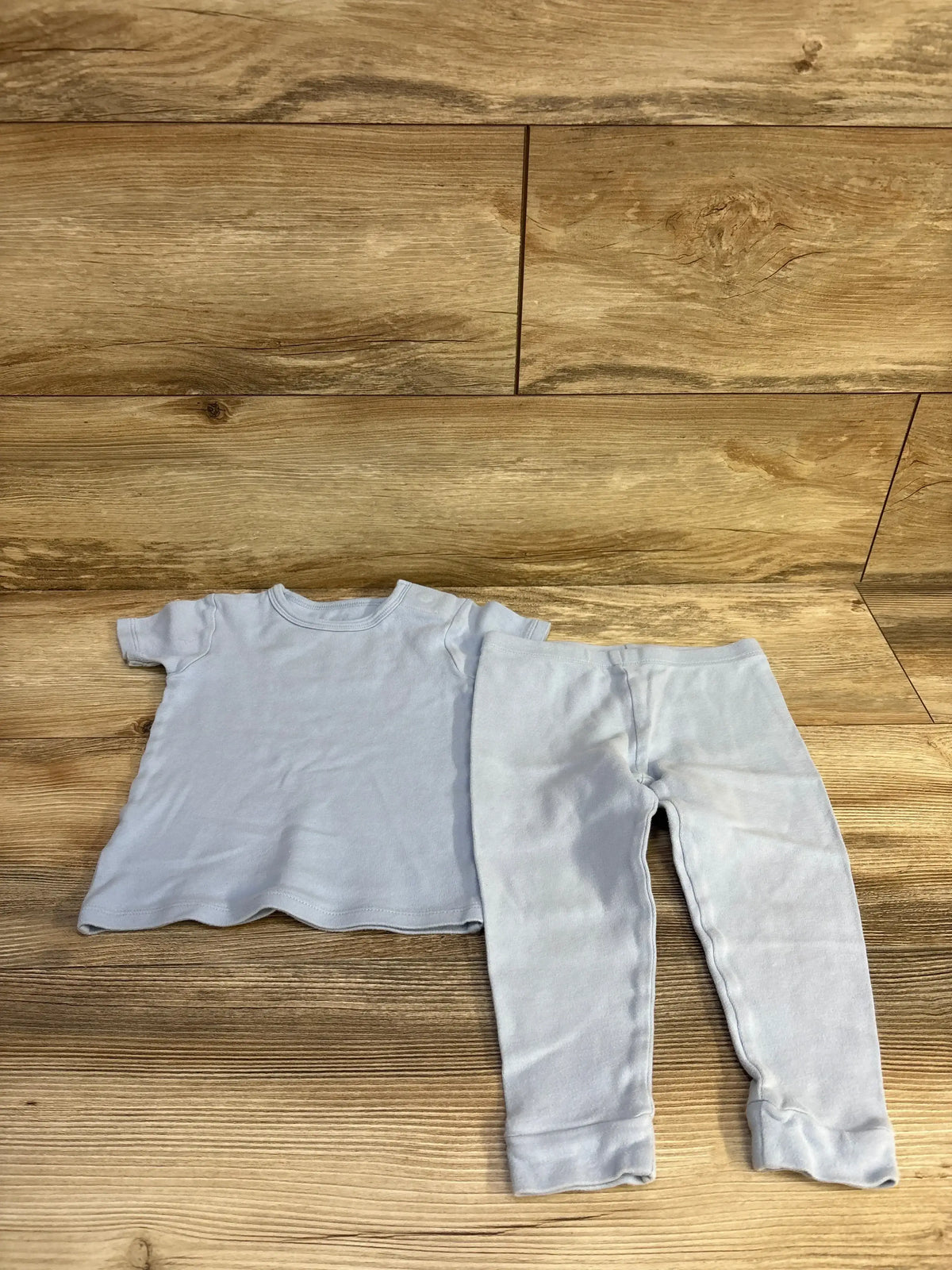 Flat lay of Magnetic Me 2-piece pajama set 2T showing light blue tee and matching leggings on wooden floor