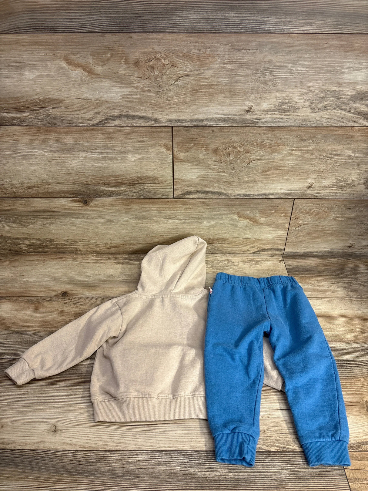 Kids beige hoodie and blue pants outfit on wood background, children's resale clothing