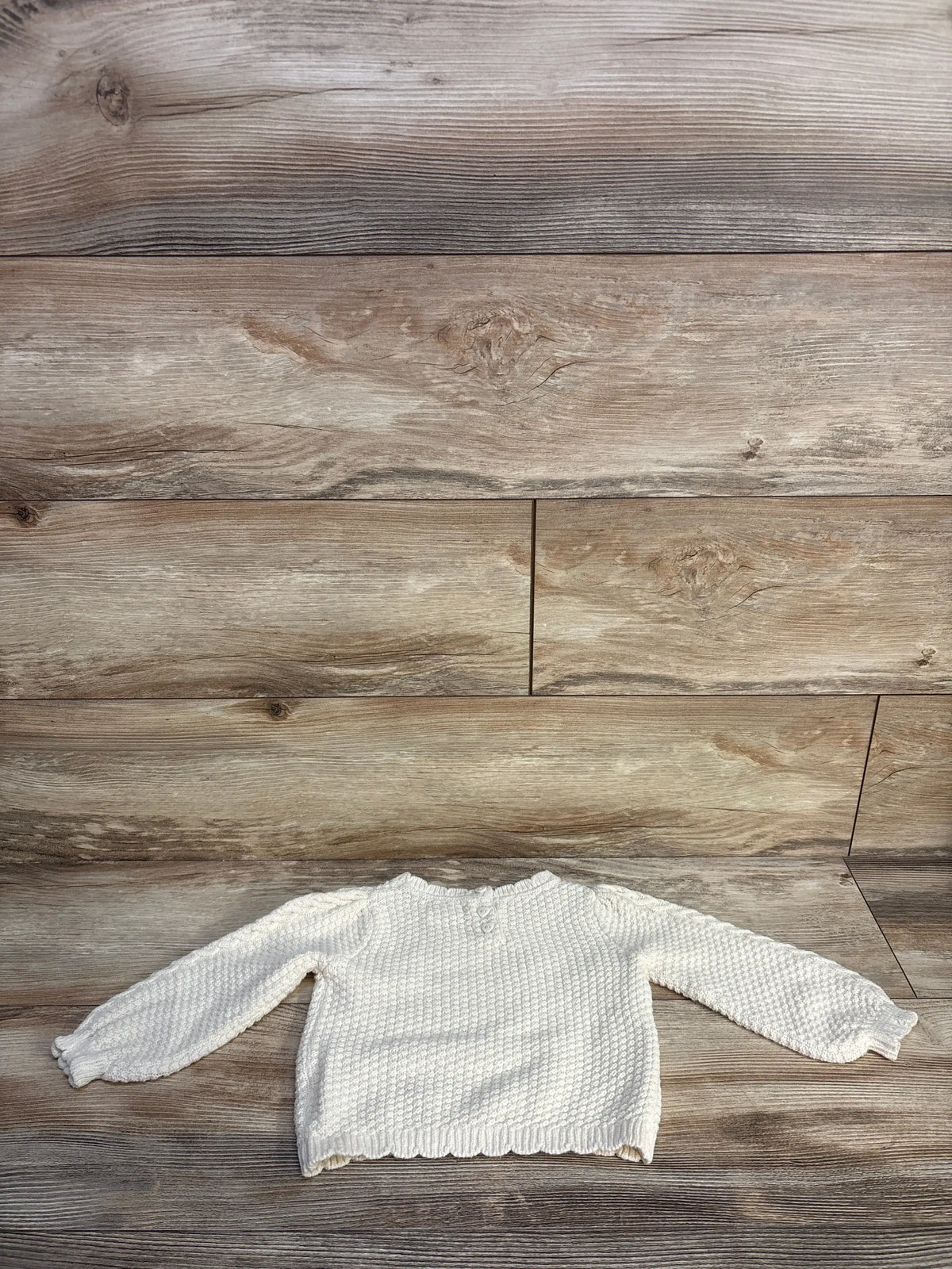 Front view of Max Studio Lil Sis sweater in ivory showcasing textured knit and ribbed trim on a wood surface