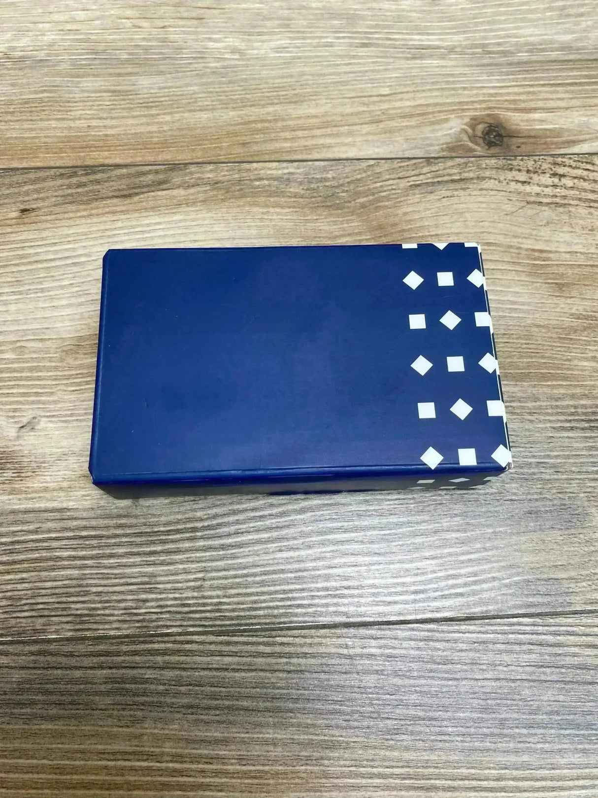 Top view of Nanit Breathing Band Wrap sz 0-3M in original blue box with white diamond pattern on wood plank background