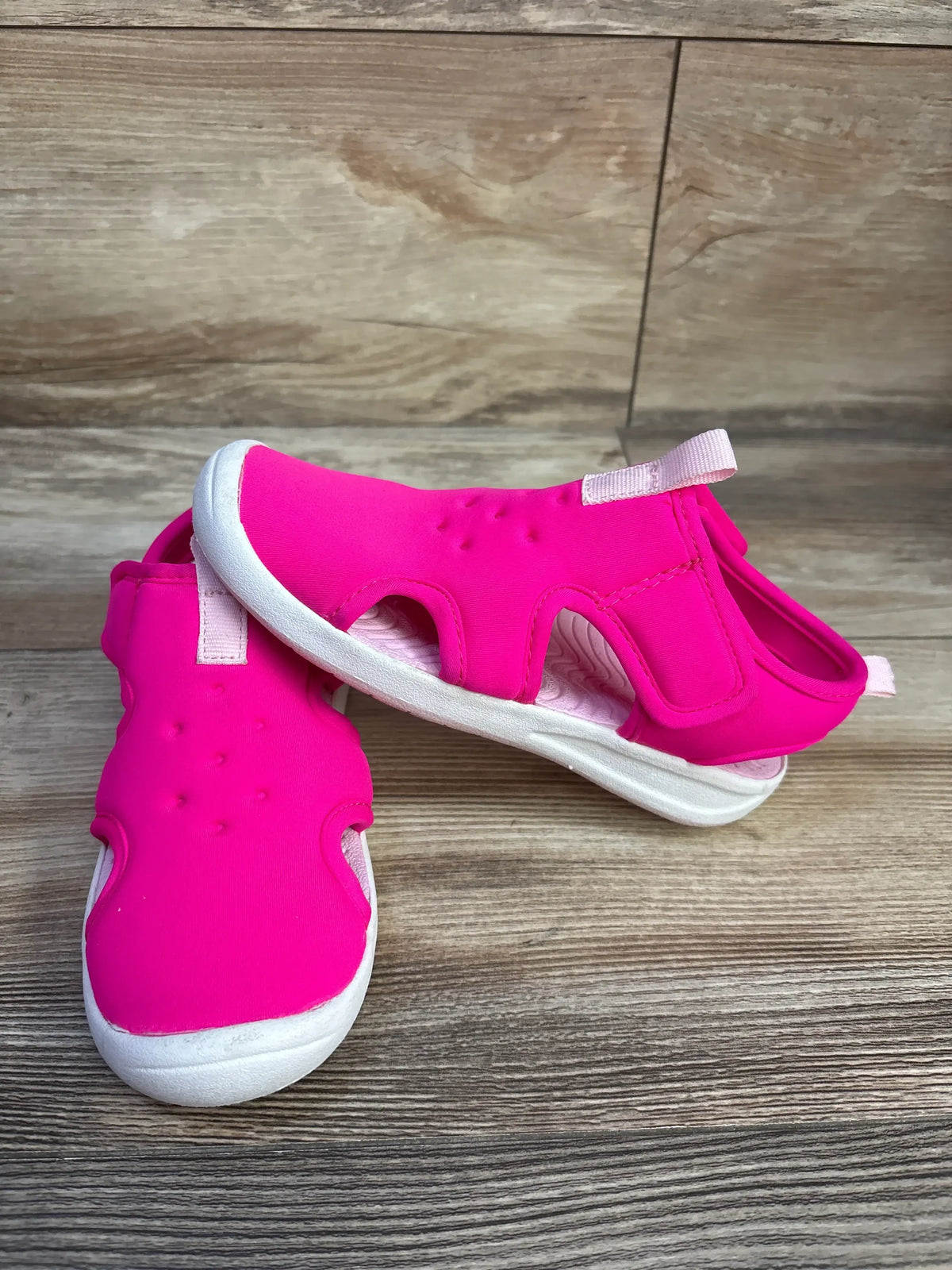 Close-up view of pink Cat & Jack Speedo water sandals showcasing hook and loop closures on a wood-grain surface
