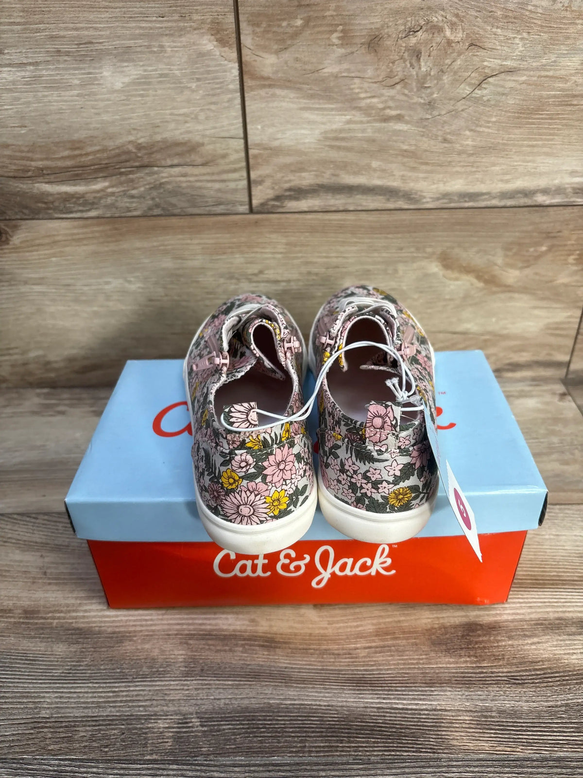 Rear view of Cat and Jack Lucian sneakers with pink and yellow floral print, double zippers, white rubber soles on Cat and Jack box