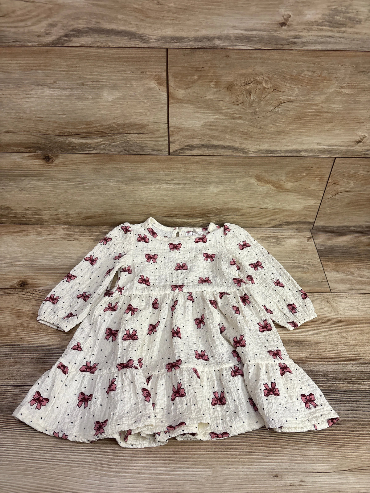 Nannette bow print ivory long sleeve baby dress for size 18m on a wood background