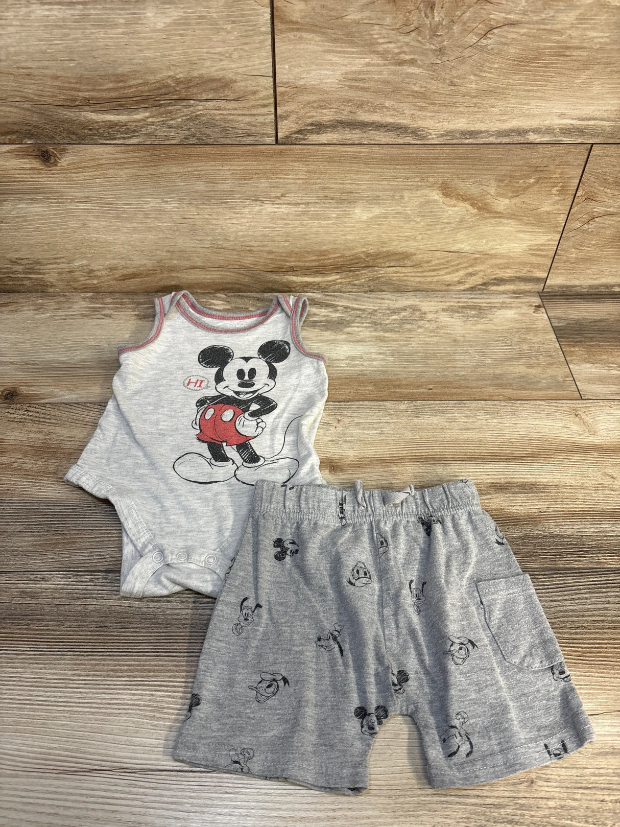 Gray baby romper and shorts set with Mickey Mouse print on wood background