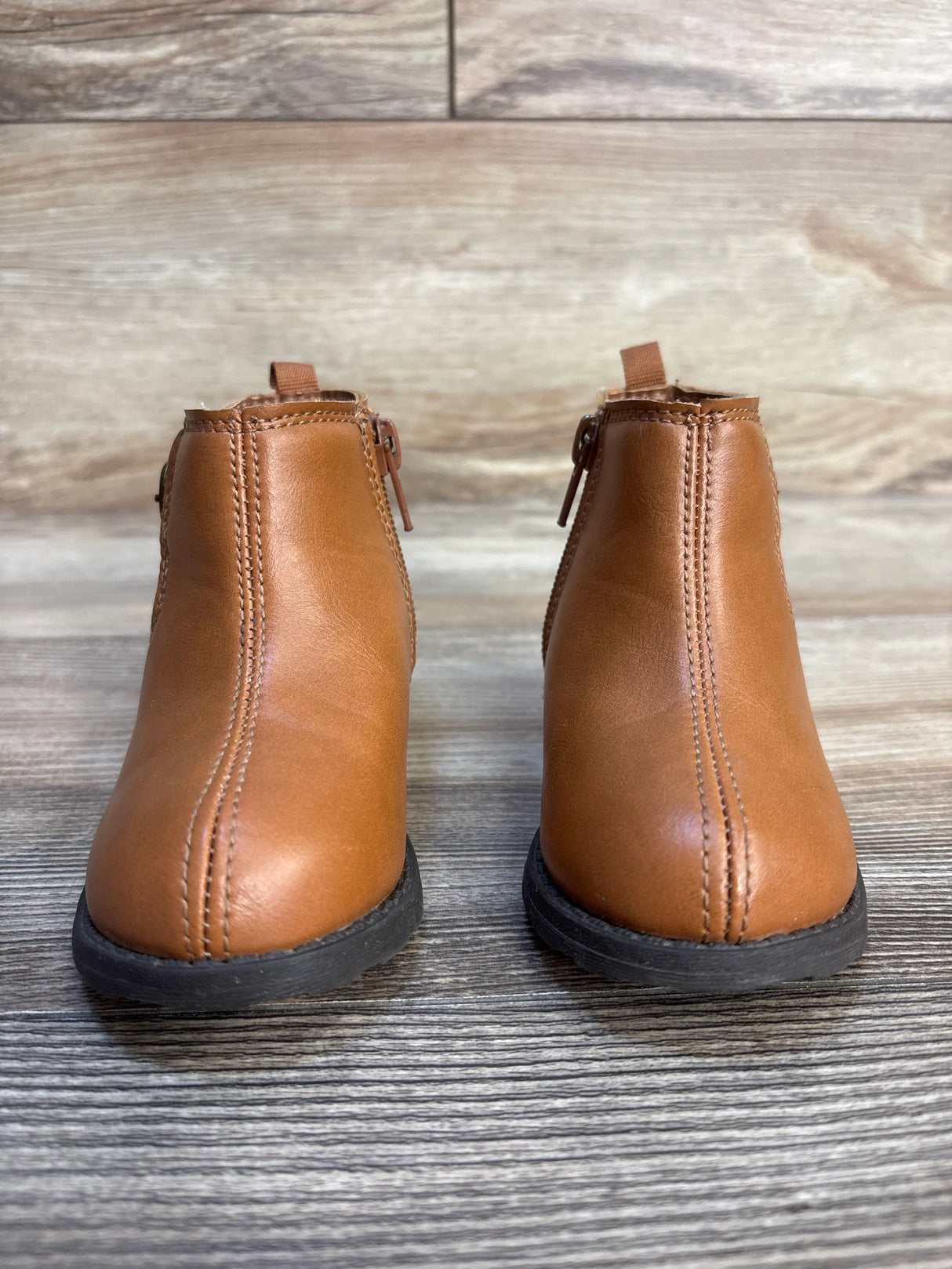 Brown toddler ankle boots with side zippers on wood background