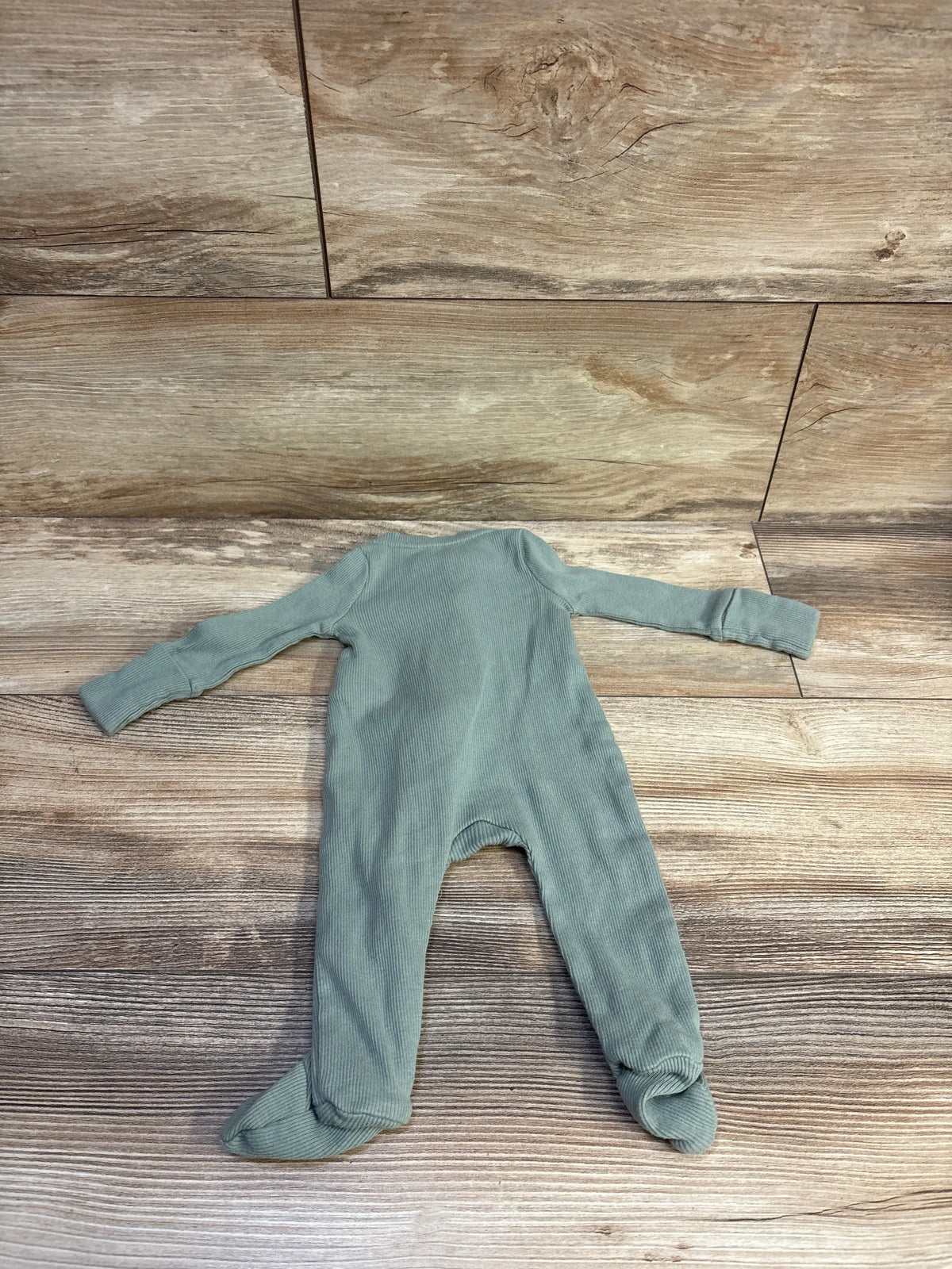 Front view of Baby Gap ribbed sleeper in soft green, showcasing long sleeves and footed legs on a wood surface