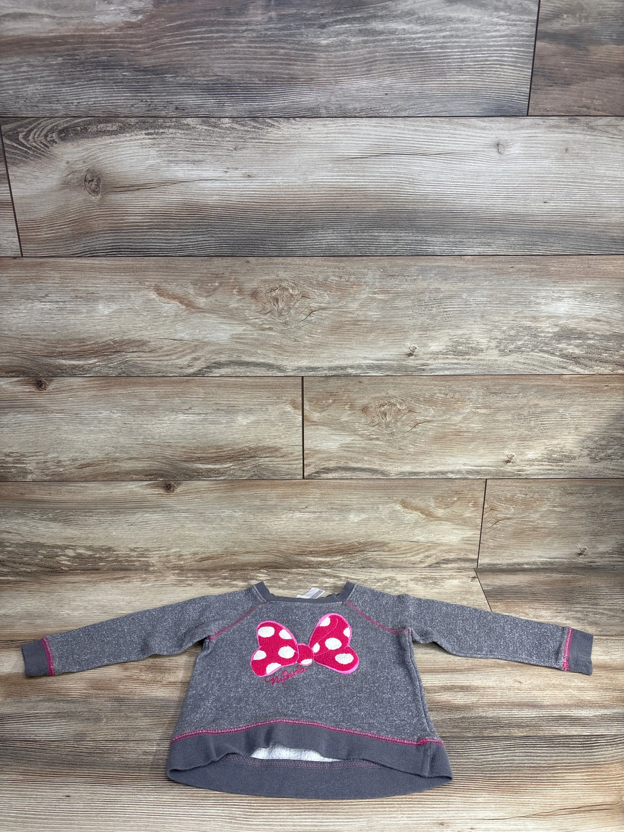 Gray toddler sweatshirt with pink polka dot bow design, displayed on wood floor background