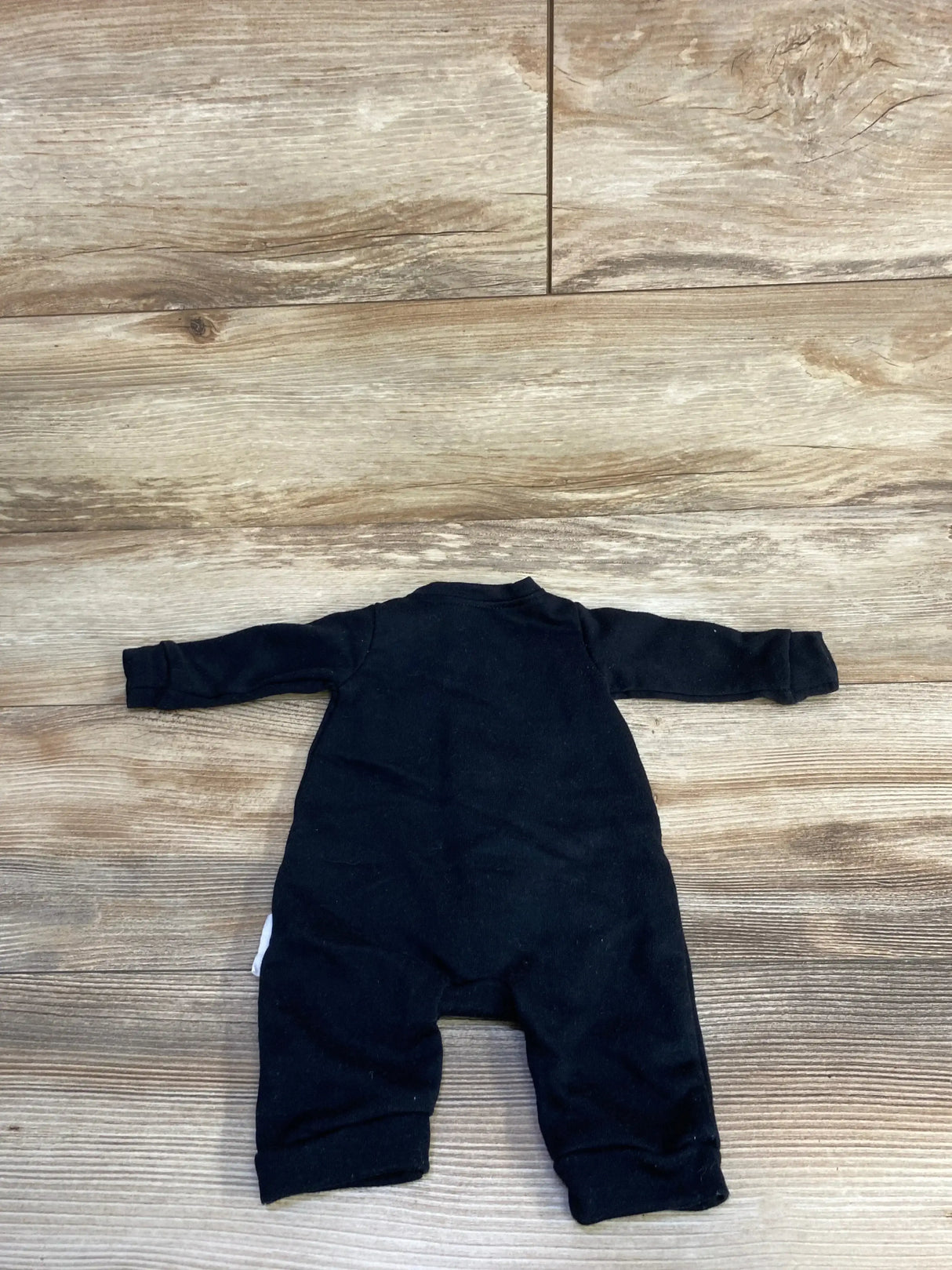 Black baby onesie laid flat on wood floor, infant clothing for newborns and toddlers