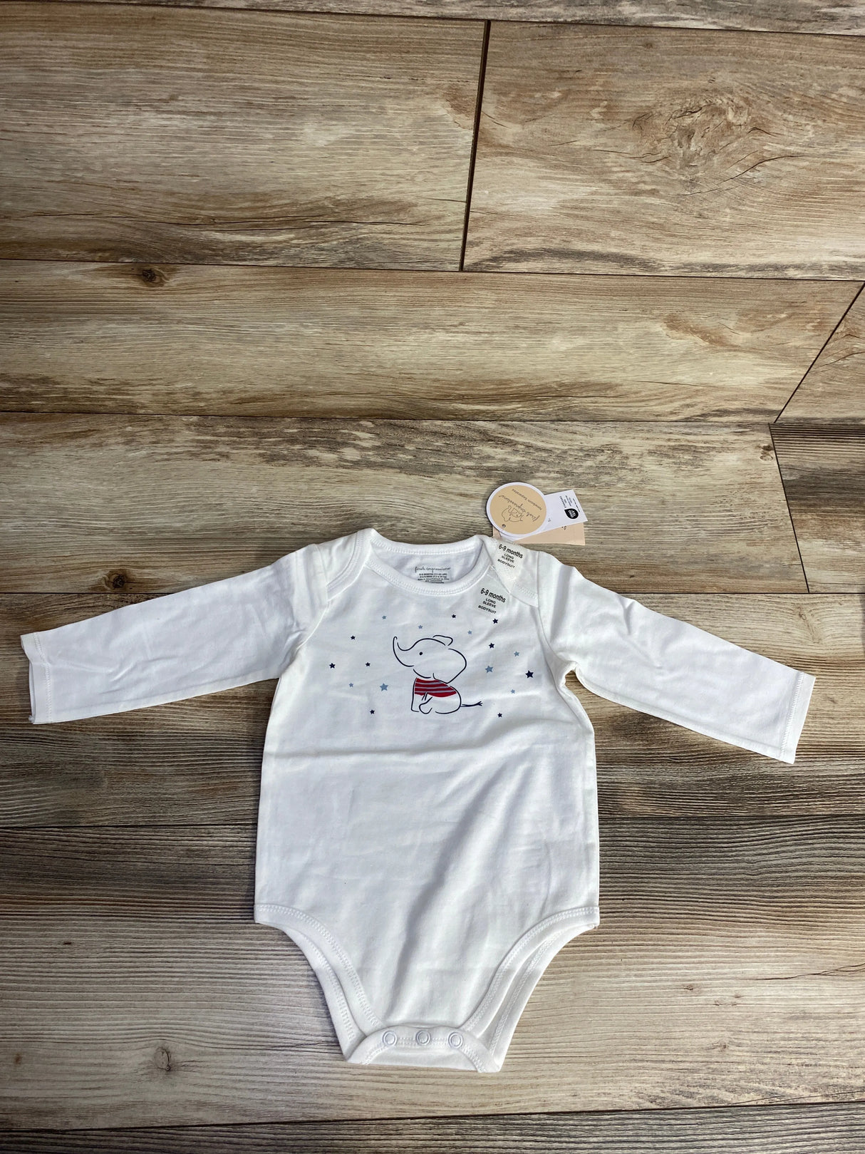 White long-sleeve baby bodysuit with cute elephant and star print on wooden floor