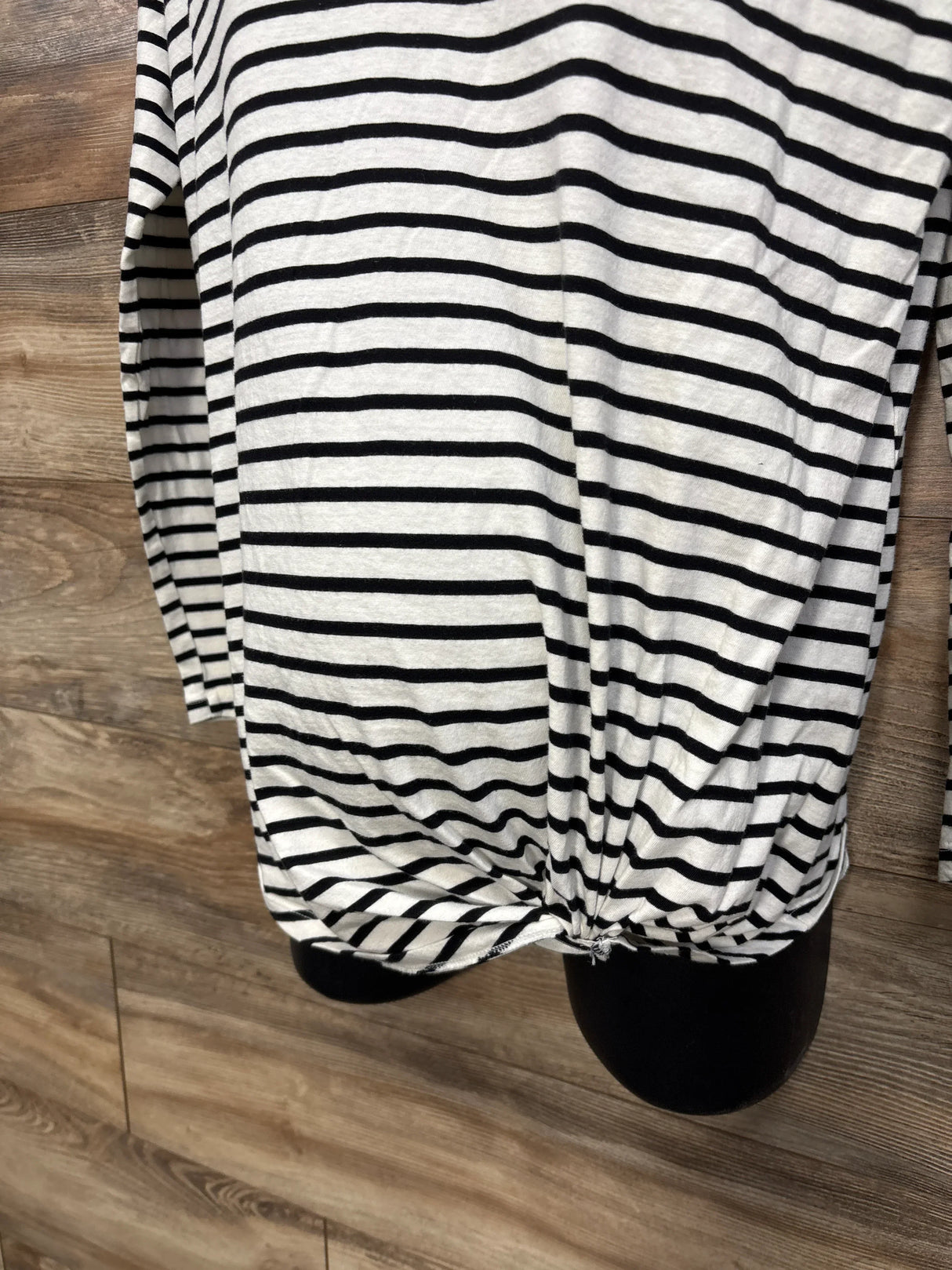 Black and white striped maternity shirt with side knot detail on wood floor background