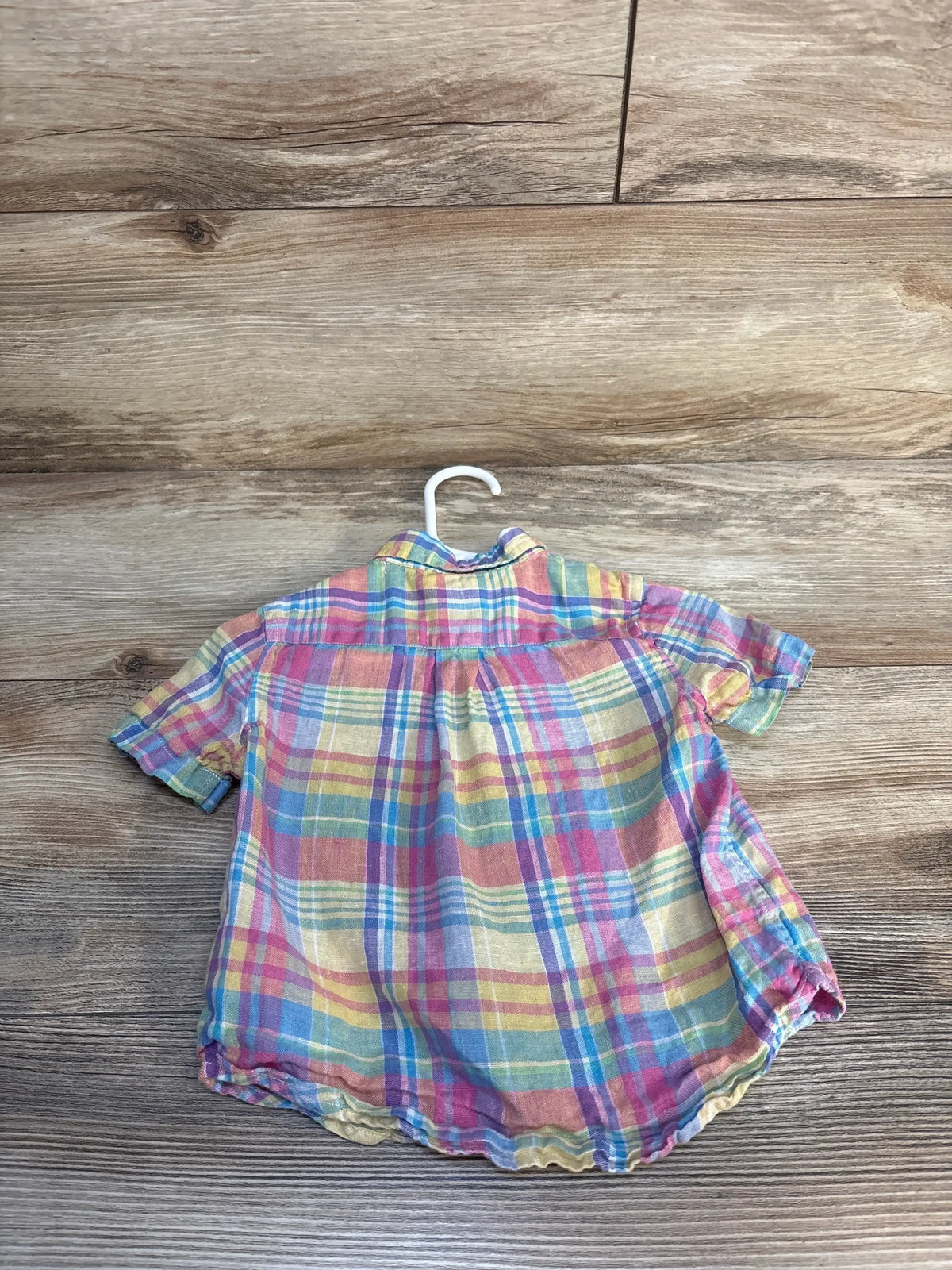 Back of toddler Ralph Lauren madras plaid button-down shirt showing yellow pink and blue plaid on wood background