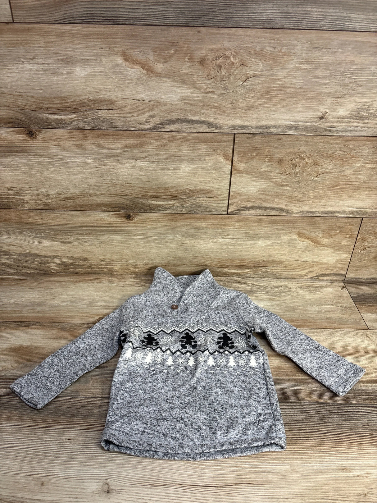 Gray knit toddler sweater with winter-themed black and white patterns on wooden background