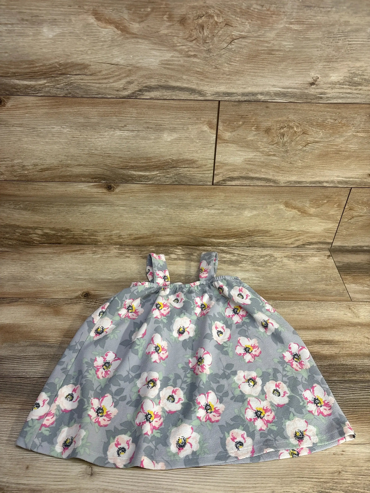 Flat lay of girls Madison Layne floral dress size 4T showcasing grey fabric with pink and white flowers on wood floor