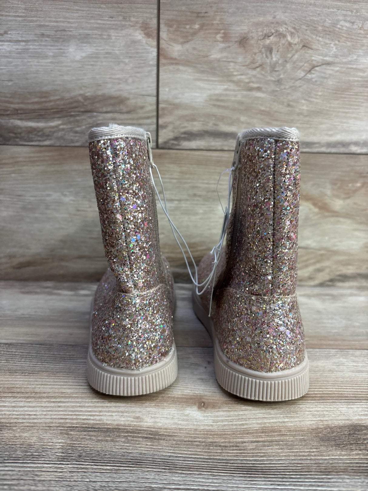 Sparkly glitter pink toddler boots with rubber soles on wood floor