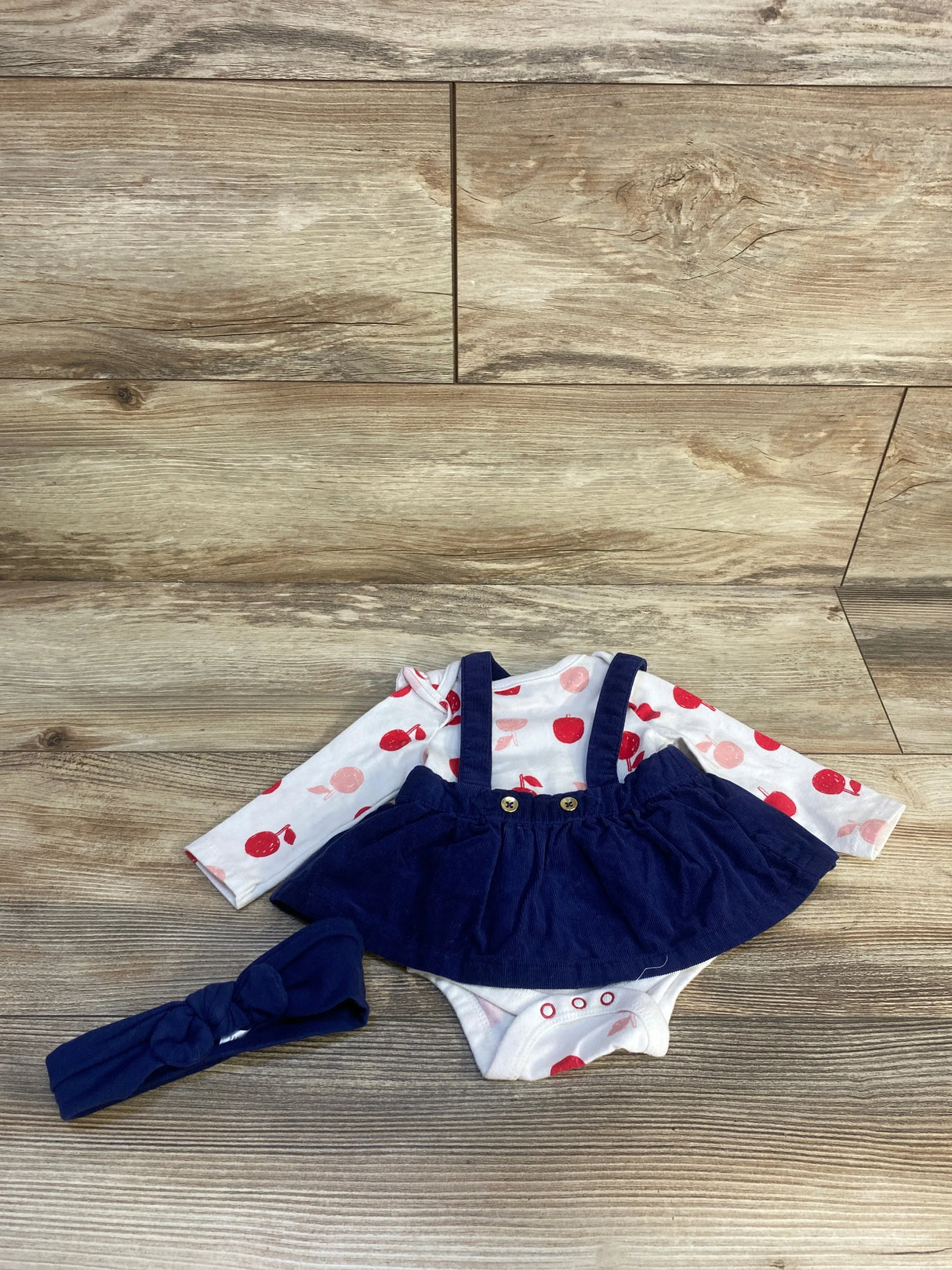 Baby girl outfit with navy skirted suspender romper, apple print onesie, and matching headband