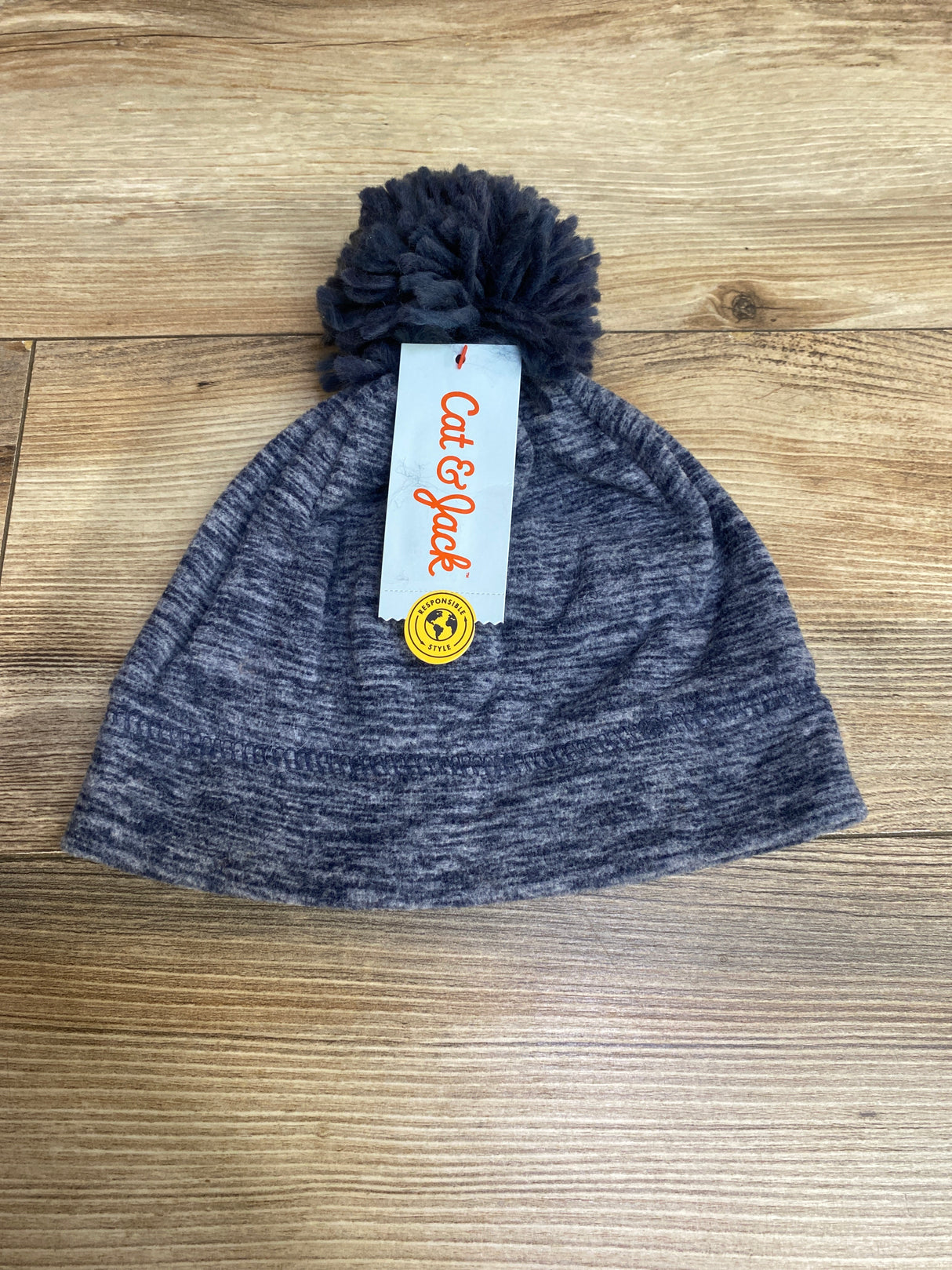Cat & Jack gray knit pom pom beanie hat with brand tag on wooden surface