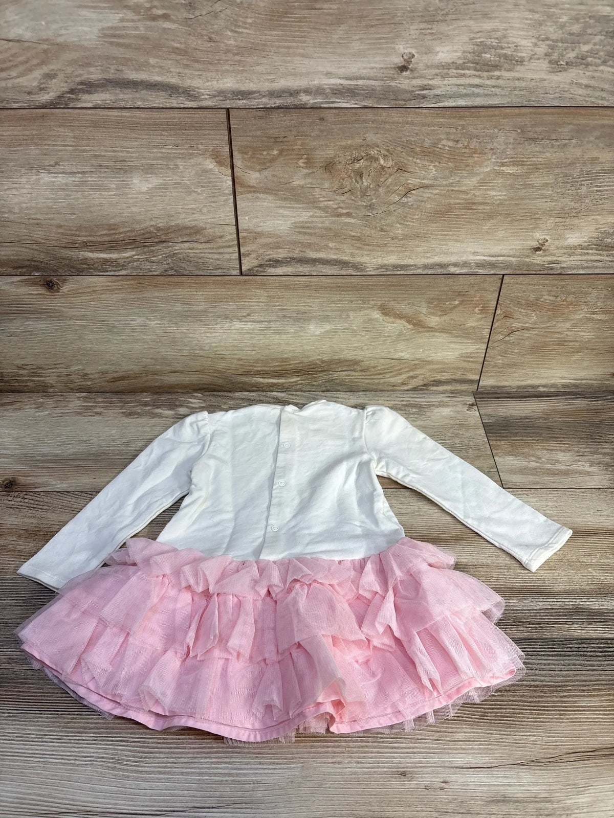 Front view of Mayoral long sleeve pink tulle dress showcasing a sparkly floral bodice and layered pink tulle skirt on wood floor