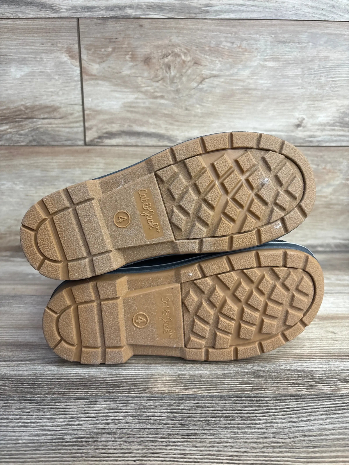 Sole view of NEW Cat and Jack Kit Winter Boots Pink sz 4Y showcasing tan lugged rubber outsoles with size 4 stamp on wood plank background