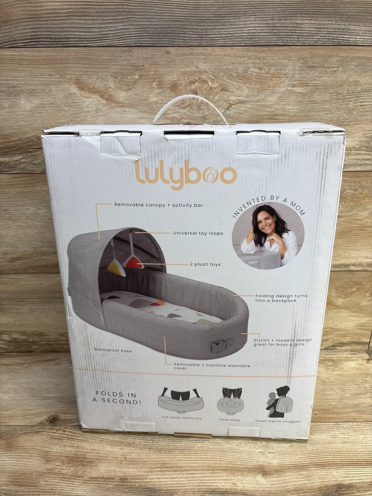 Lulyboo gray portable baby lounger with canopy and toys, folds into backpack, in retail box.