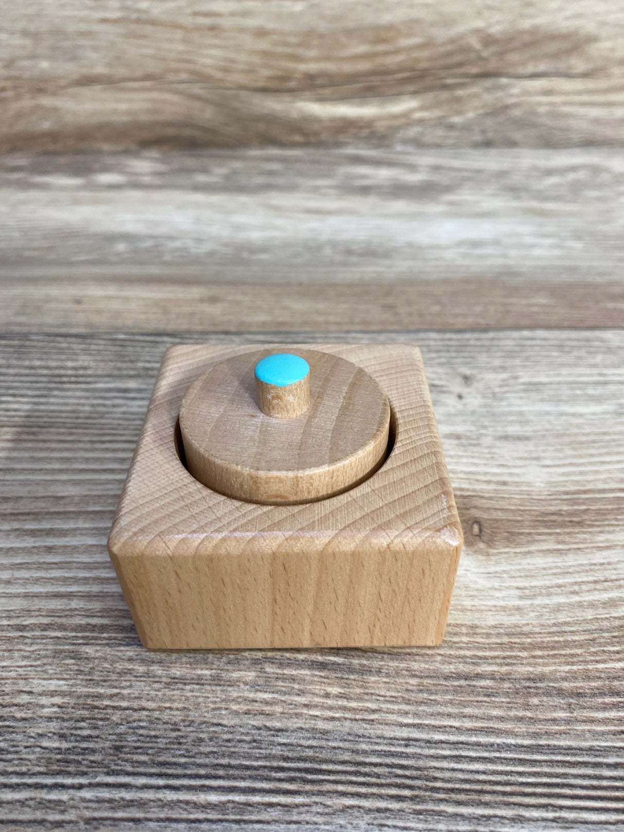 Wooden Montessori toy box with round blue knob on natural wood background