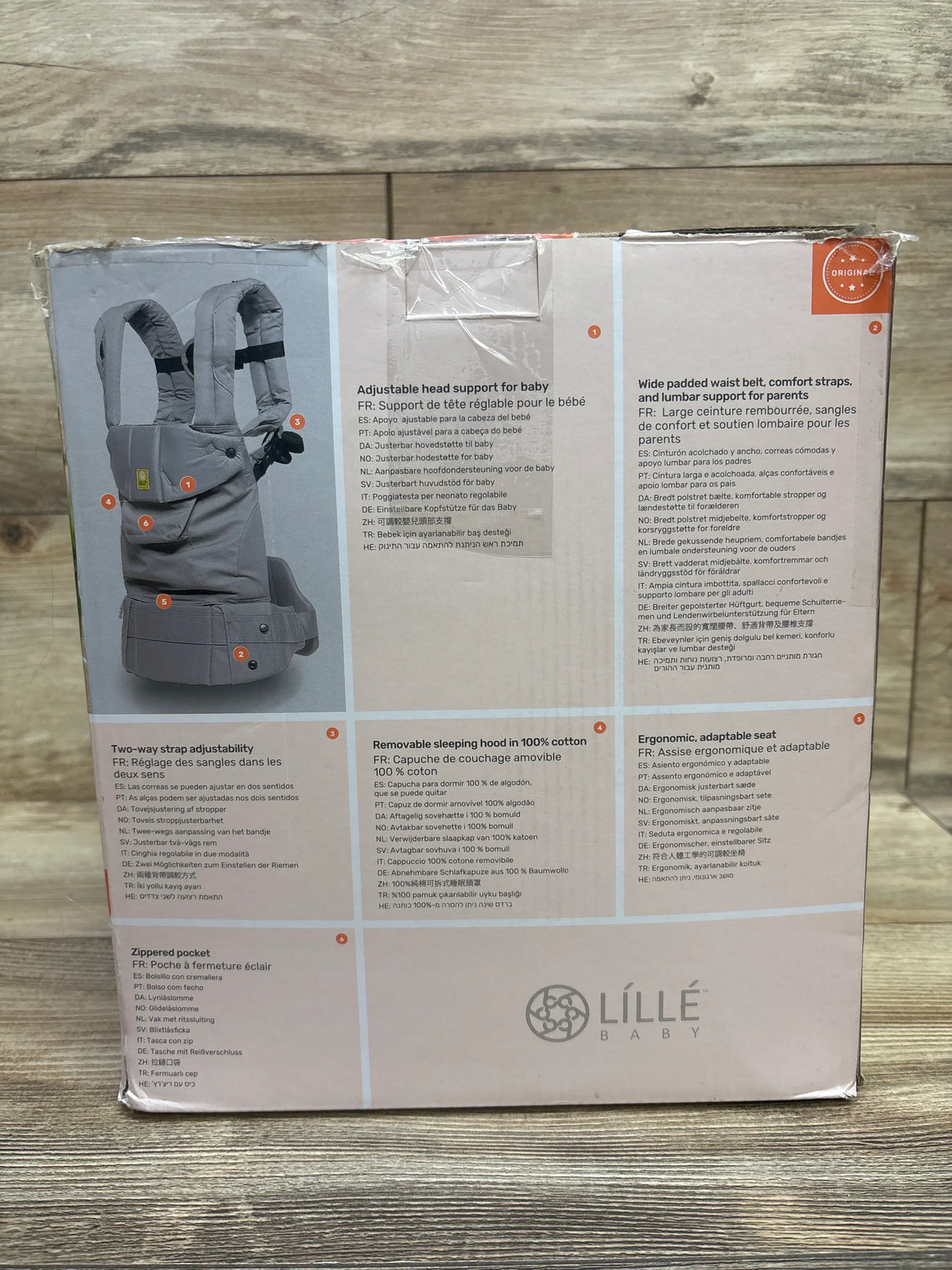 Lillebaby baby carrier packaging showing gray adjustable carrier with padded waist belt, ergonomic seat, two-way strap, and removable cotton hood