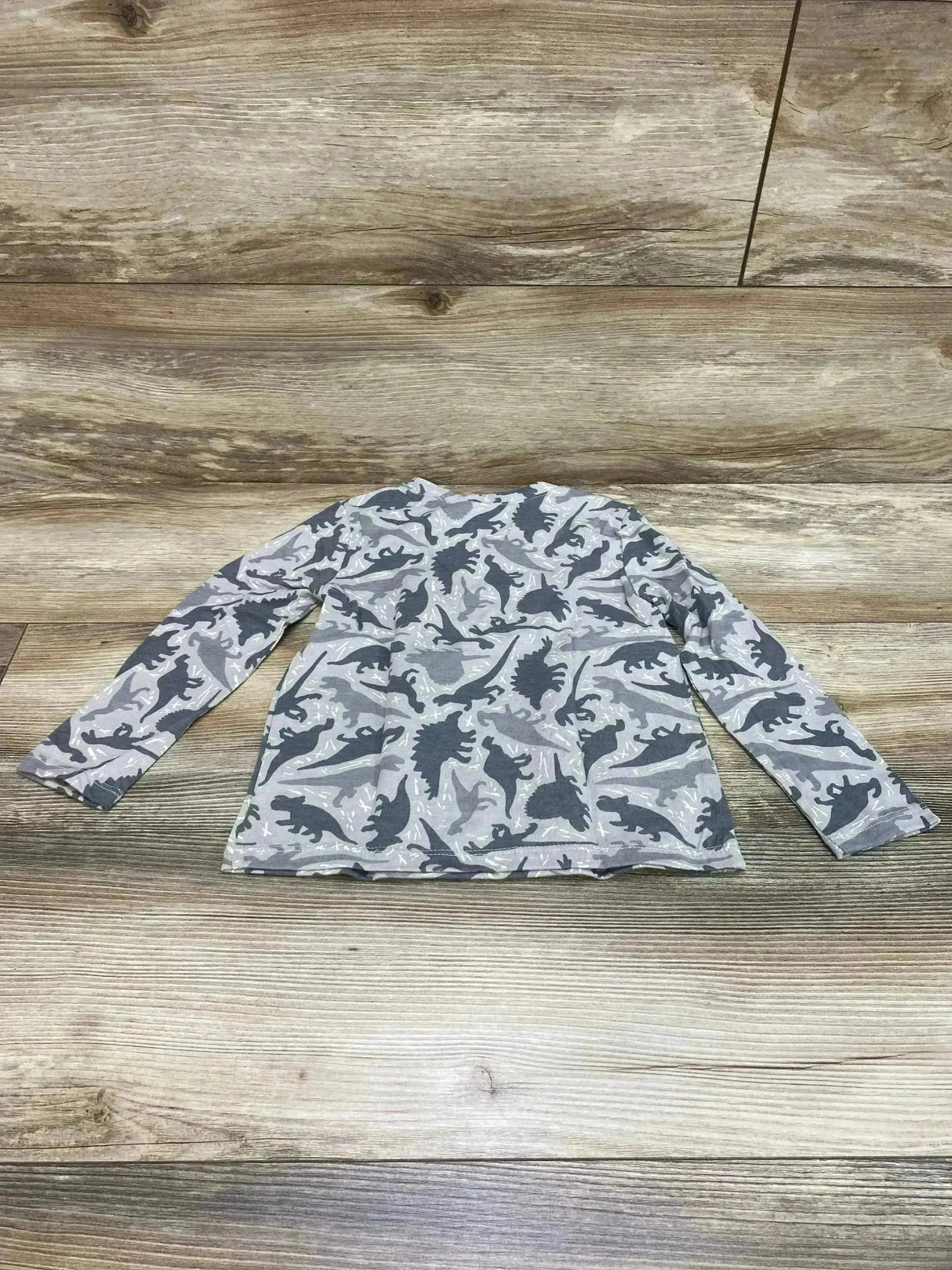 Flat-lay back view of Old Navy 4T grey long-sleeve toddler T-shirt showing all-over dark grey dinosaur print on wood background
