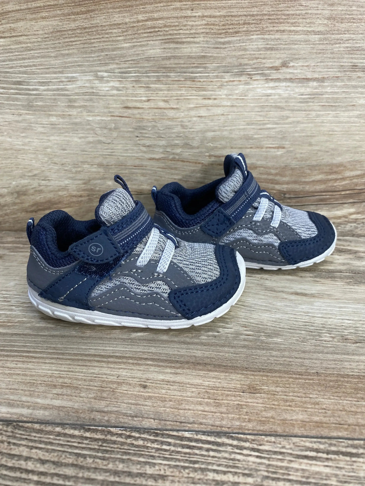 Front-side view of toddler Stride Rite Kylo navy sneakers showing mesh upper and hook-and-loop strap on wood-grain surface