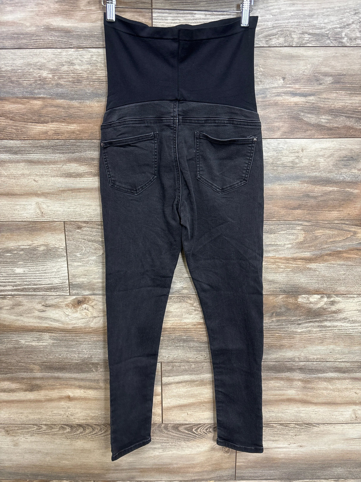 Black maternity jeans with over-the-belly panel, back view on hanger