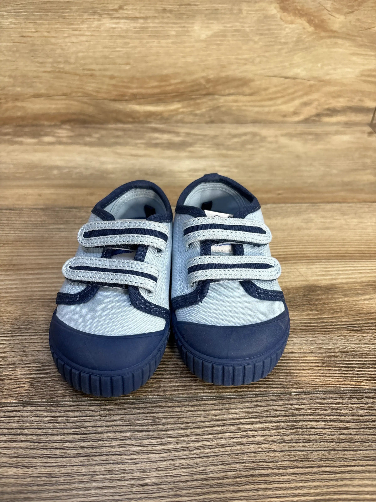 Front view of Magical Internet Money Two Strap Bump Tow Sneakers showcasing two straps and navy rubber toe caps on a wood floor