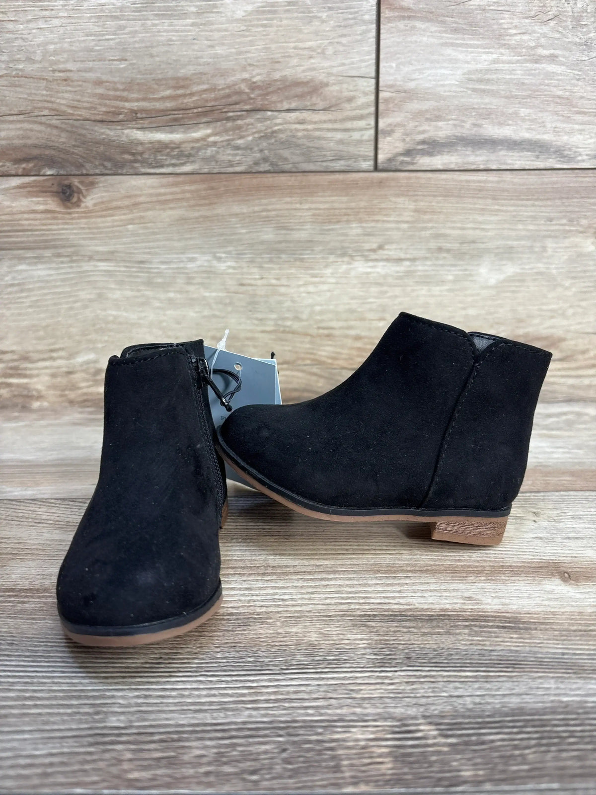 Black suede ankle boots with brown sole on wooden background
