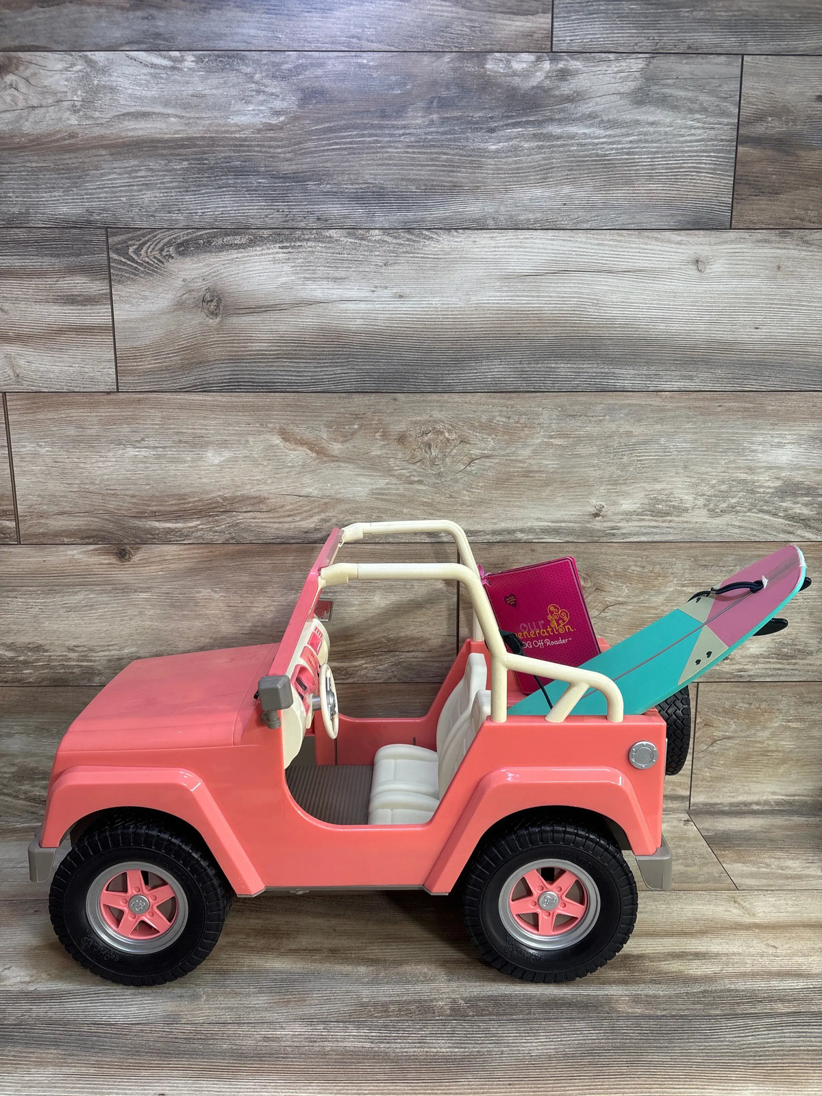 Pink Our Generation Off-Roader 4x4 doll vehicle with a surfboard and accessory book