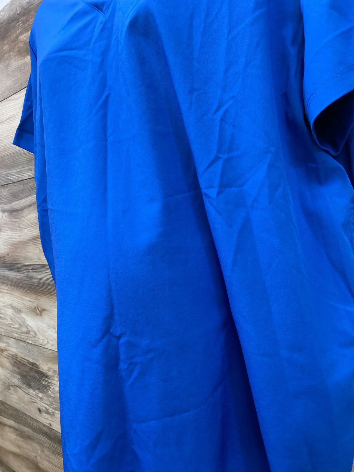 Front view of XL maternity scrub top showcasing royal blue cooling knit fabric and short sleeves on wood background