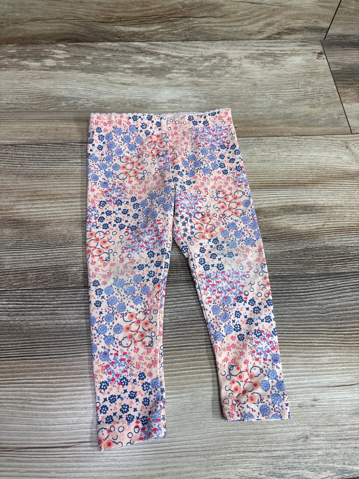 Tea Collection pink floral pattern leggings for baby size 9-12m on a wood floor