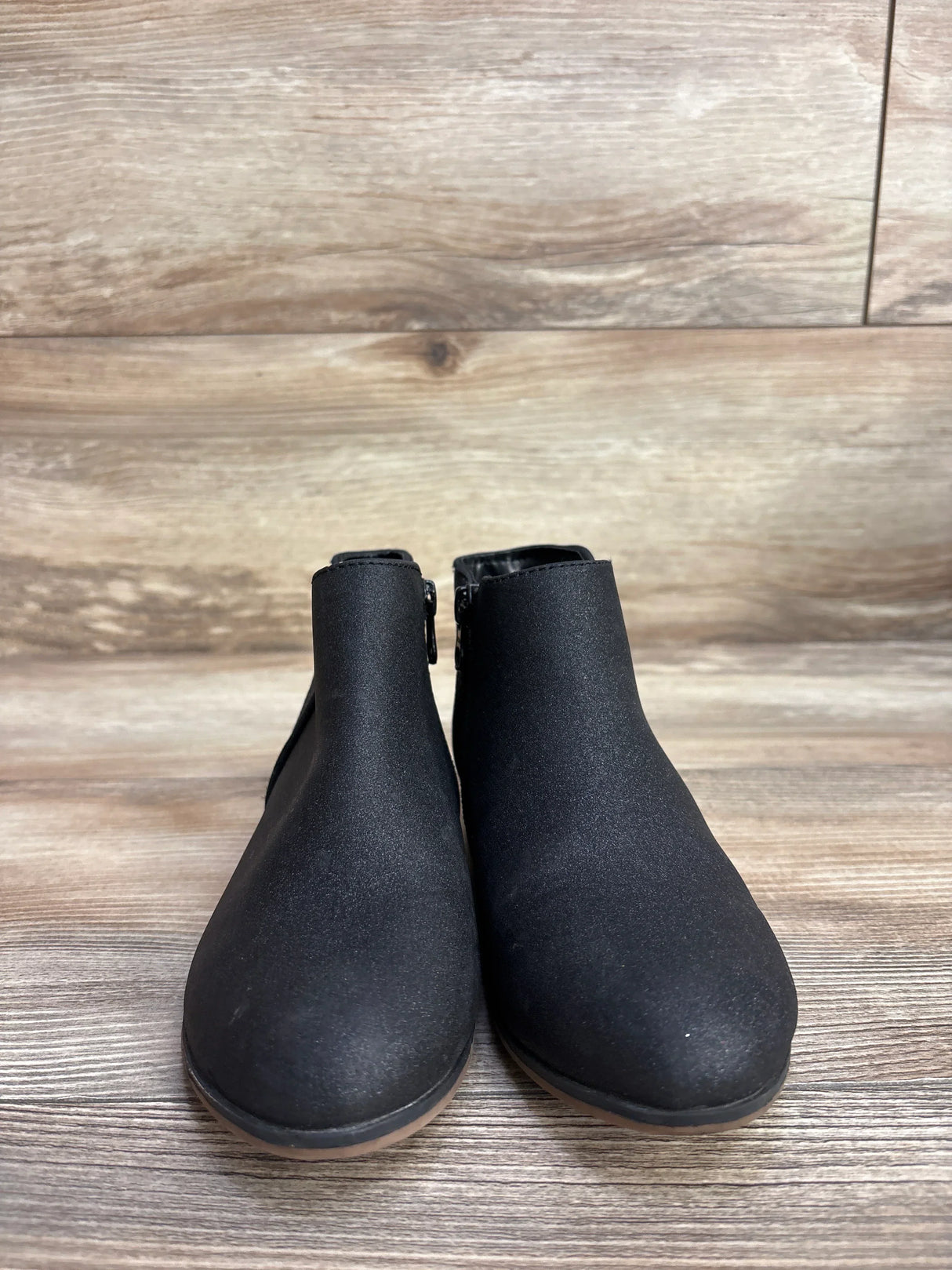 Pair of black ankle boots for kids on wood background