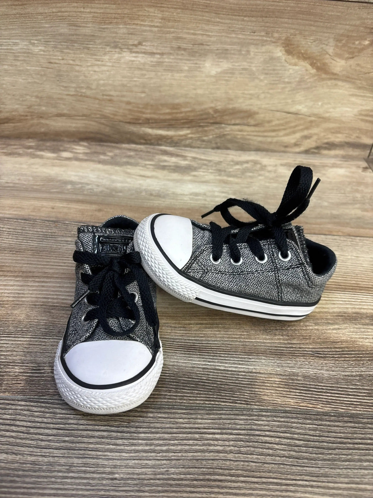 Angled front view of Converse Madison Ox low-top sneaker in heather grey showcasing white toe cap and black laces on wood background