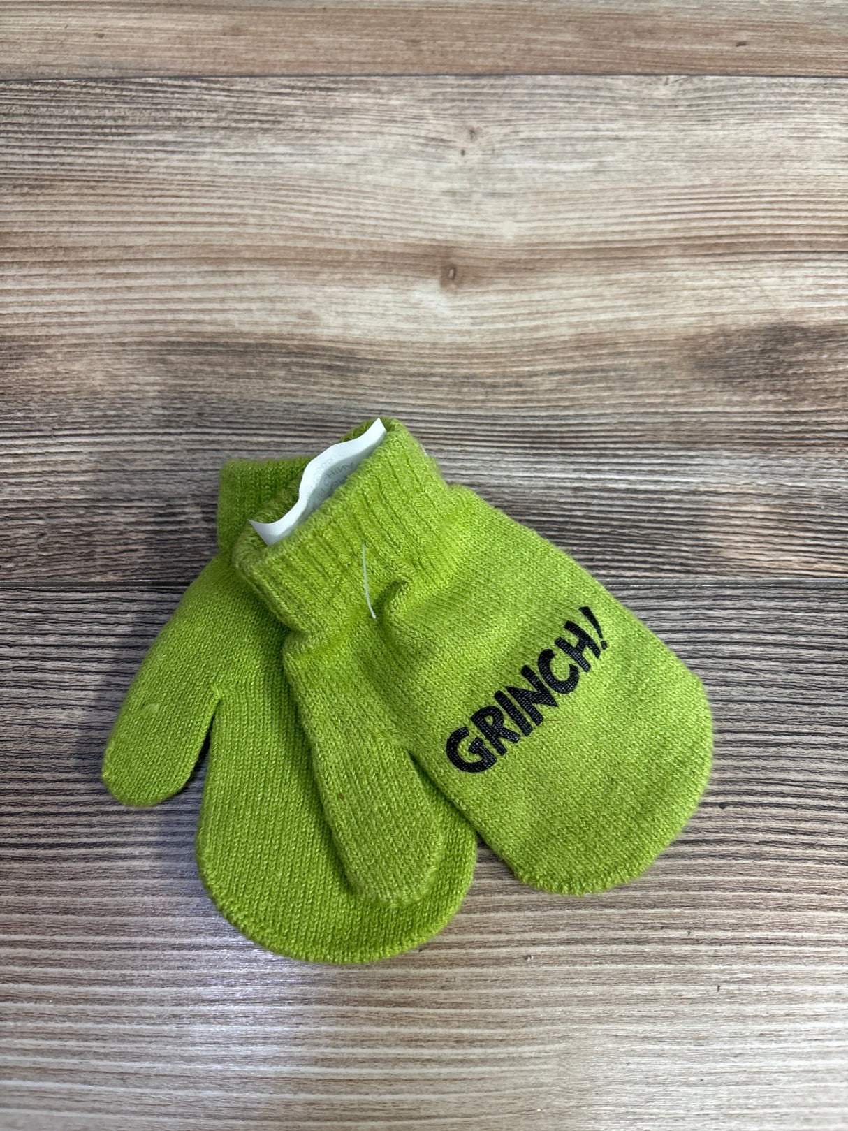 Pair of bright green children's knit mittens with ribbed cuffs, one mitten printed with the word GRINCH!