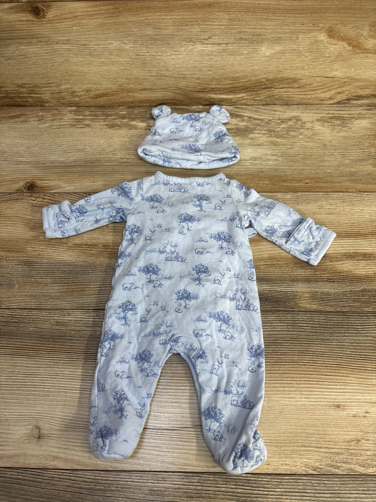 Blue and white baby sleeper and hat set with bear ears and animal print on wood background