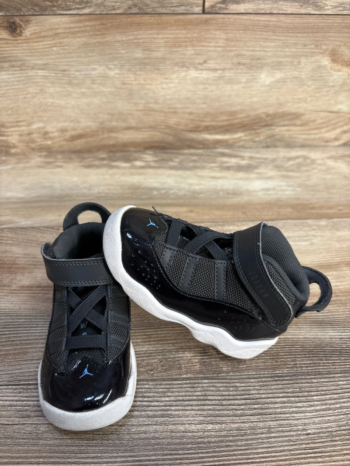 Black toddler Jordan sneakers with white soles on wooden floor