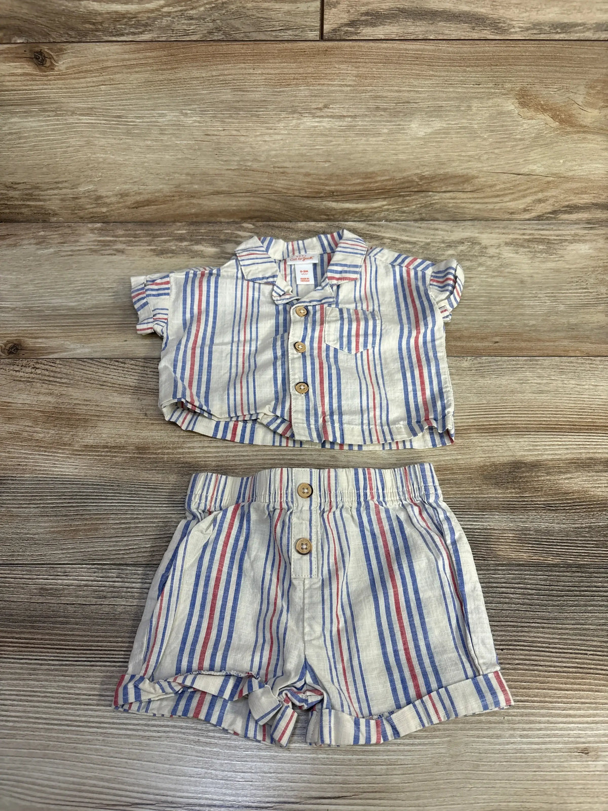 Flat lay of cream striped button-up baby shirt and matching shorts, newborn 0-3 months, on white background