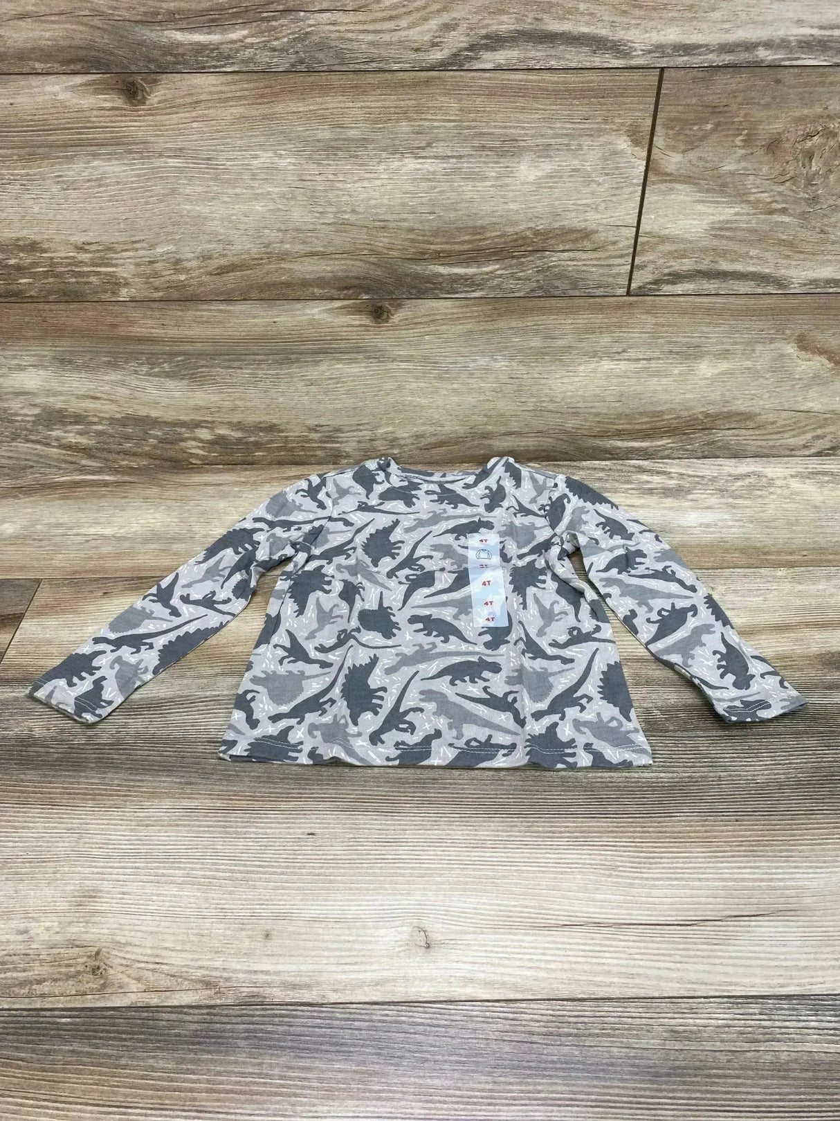 Flat lay of grey Old Navy long-sleeve toddler T-shirt with dark dinosaur print and visible 4T size tag on wood background