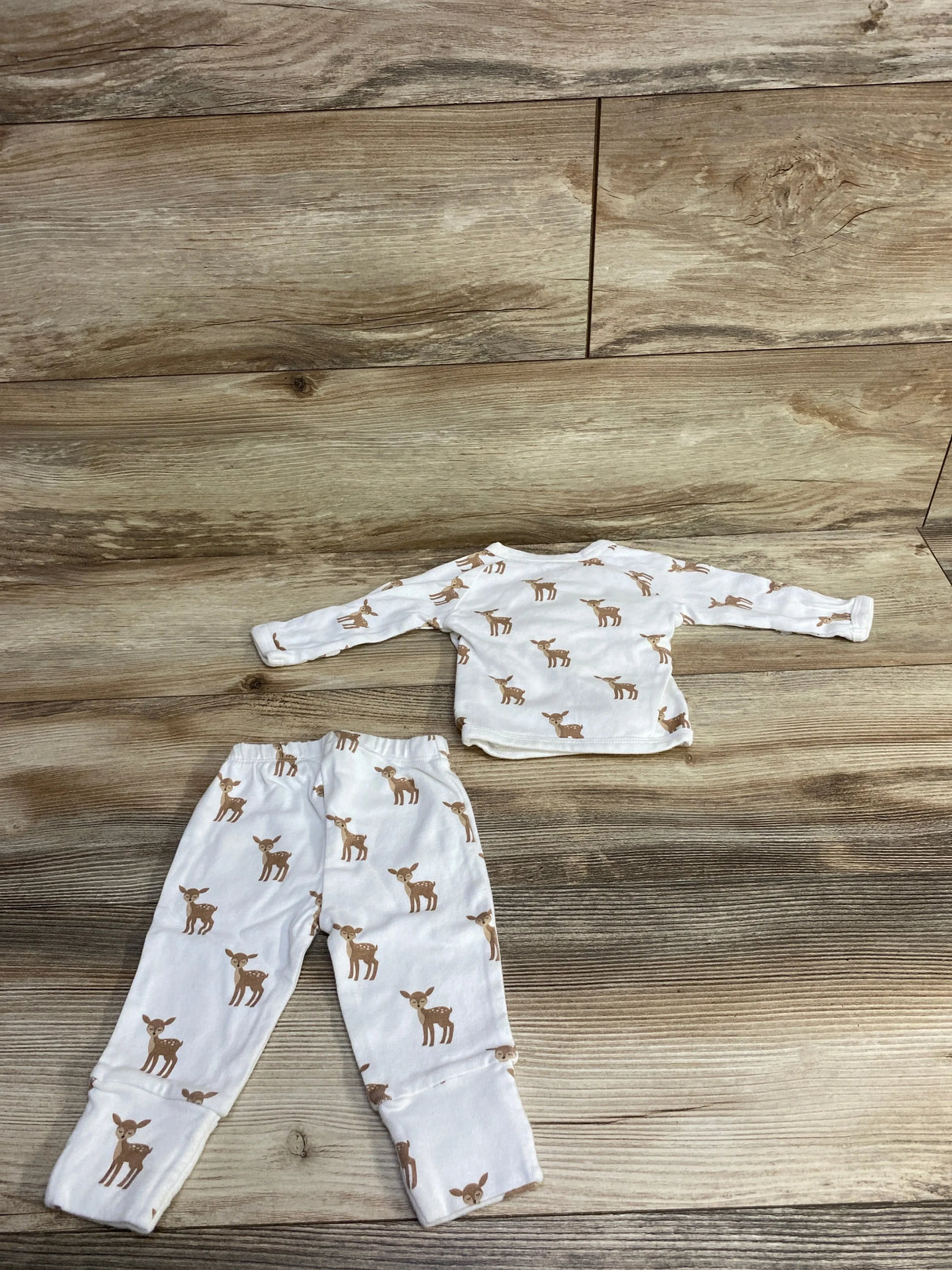 White children's pajama set with brown deer print on wooden floor background