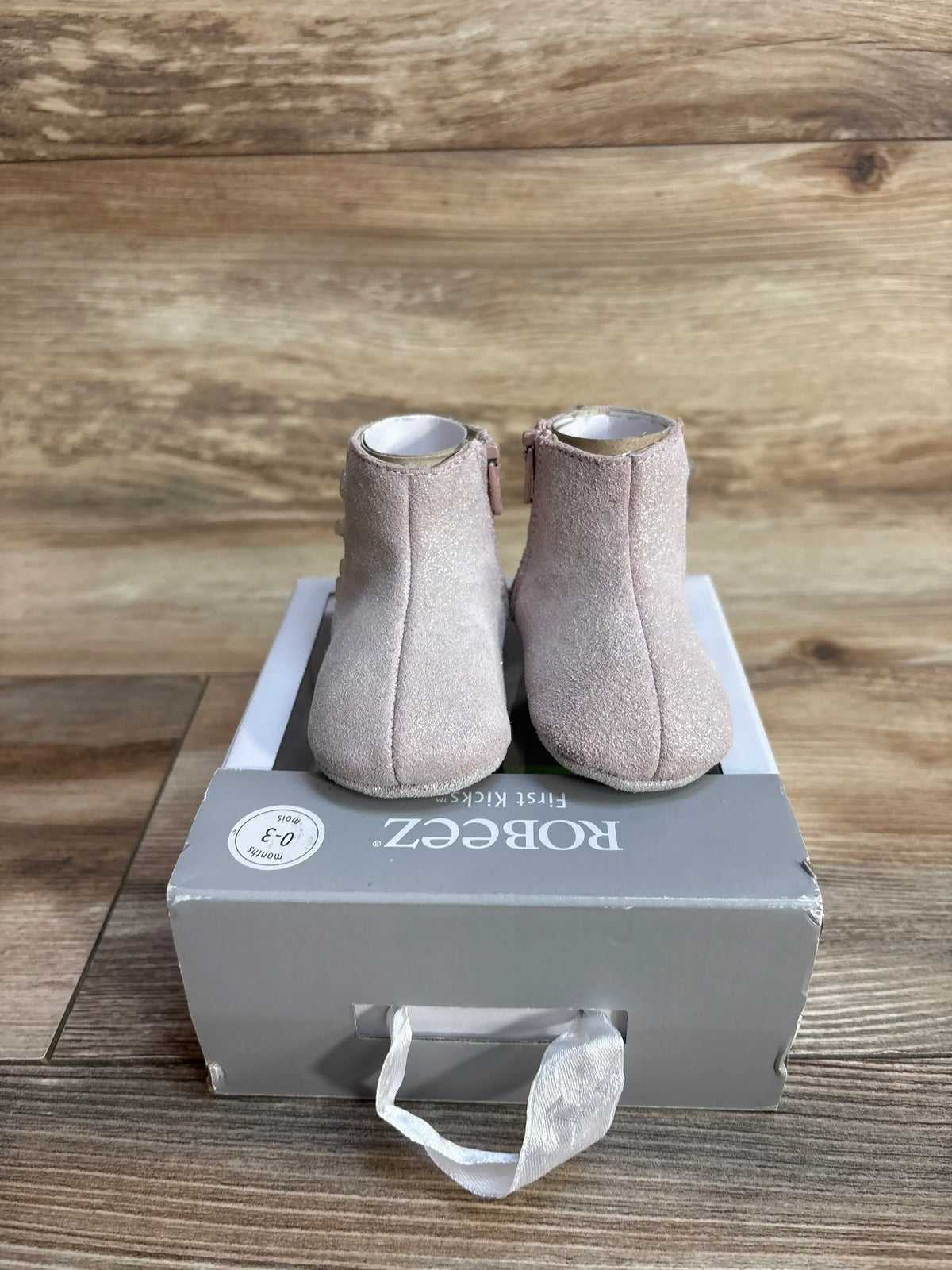 Pair of light pink suede baby booties on gray Robeez box labeled 0-3 months