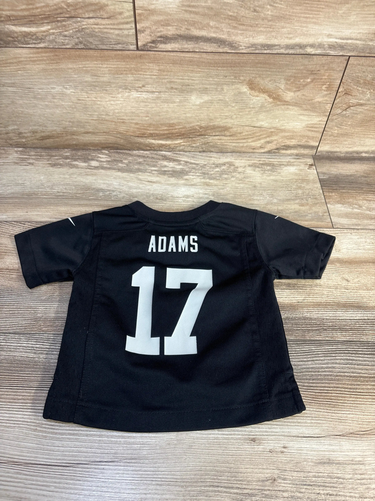 Back view of black Nike Las Vegas Raiders Davante Adams jersey in size 12 months showcasing ADAMS and 17 on wood floor