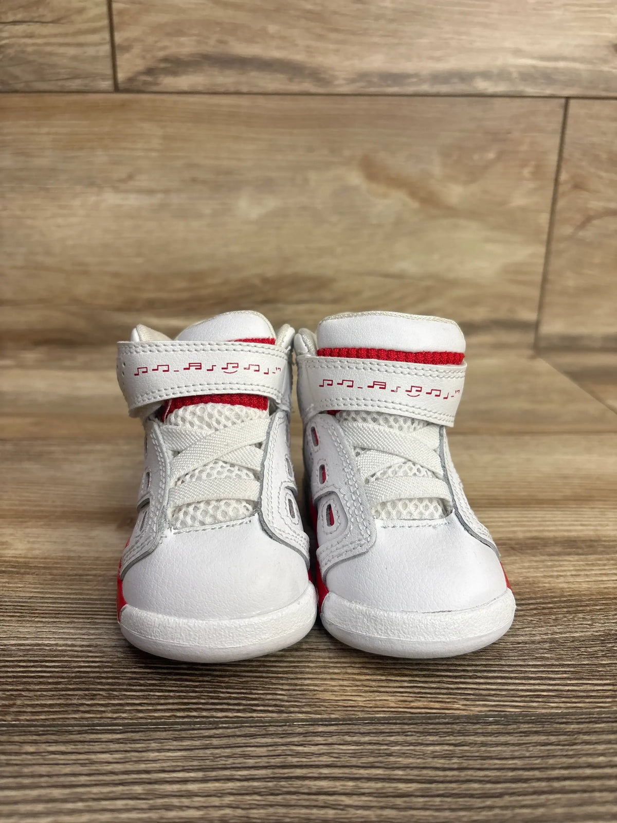 Front of Air Jordan 6-17-23 (TD) sneakers in white/university red with musical-note Velcro straps and mesh, on wood floor