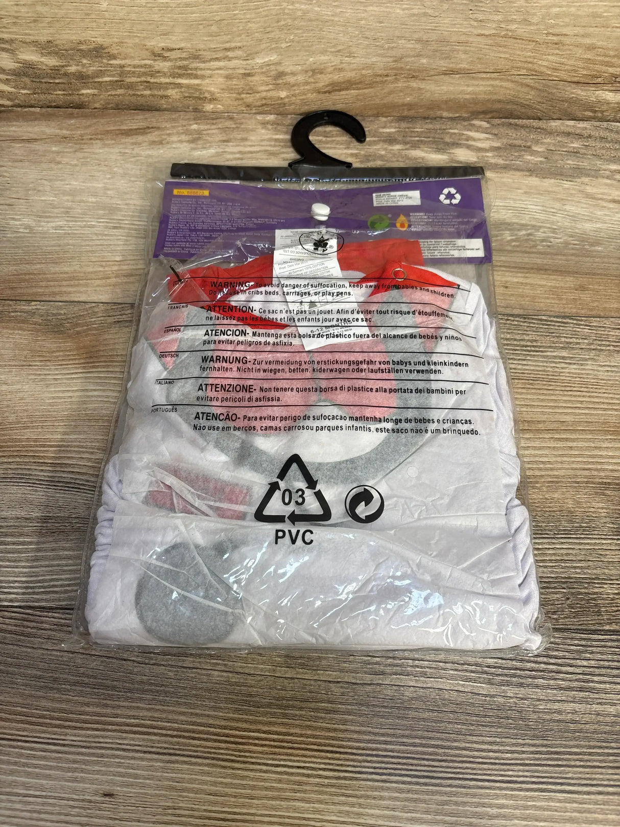 Packaged view of Rubie’s Baby’s 1st Halloween nurse costume, size 6-12 months, with white and red design on a wood-grain surface