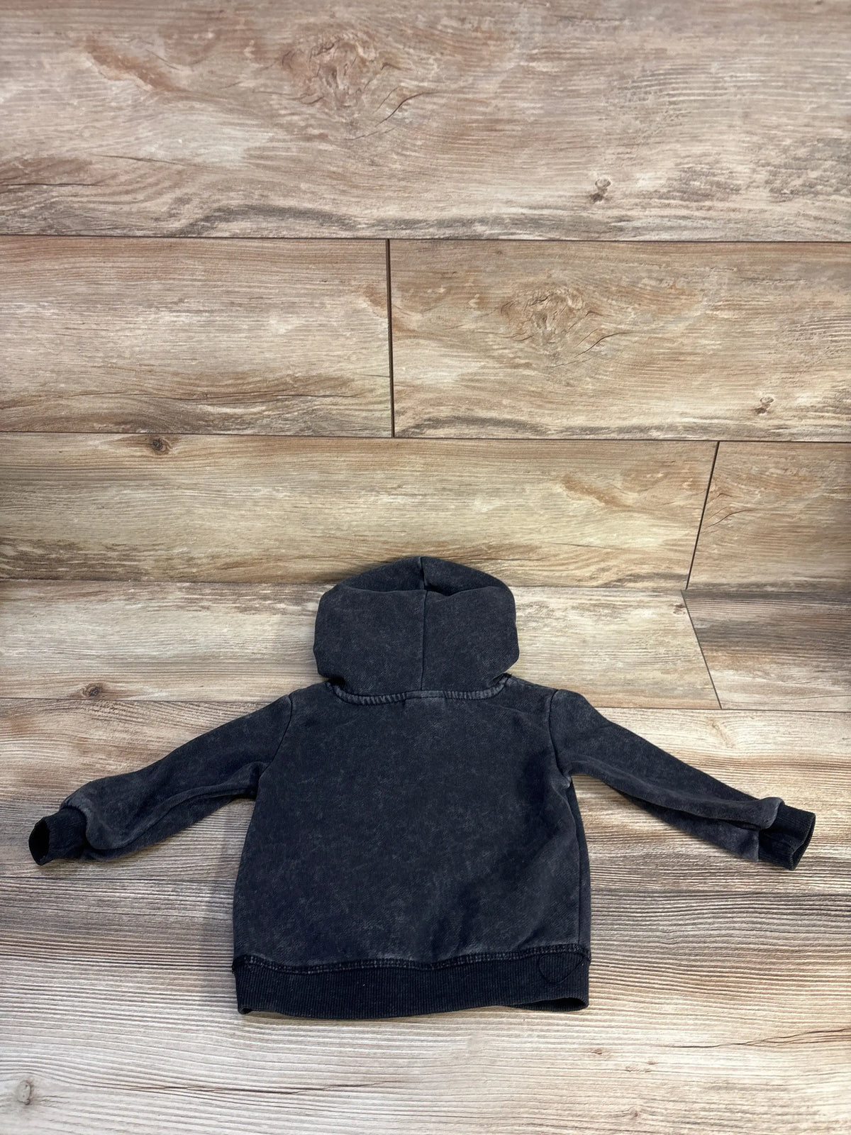 Back view of The Rolling Stones grey hooded sweatshirt showcasing the hood, long sleeves, and ribbed hem on a wood-look floor