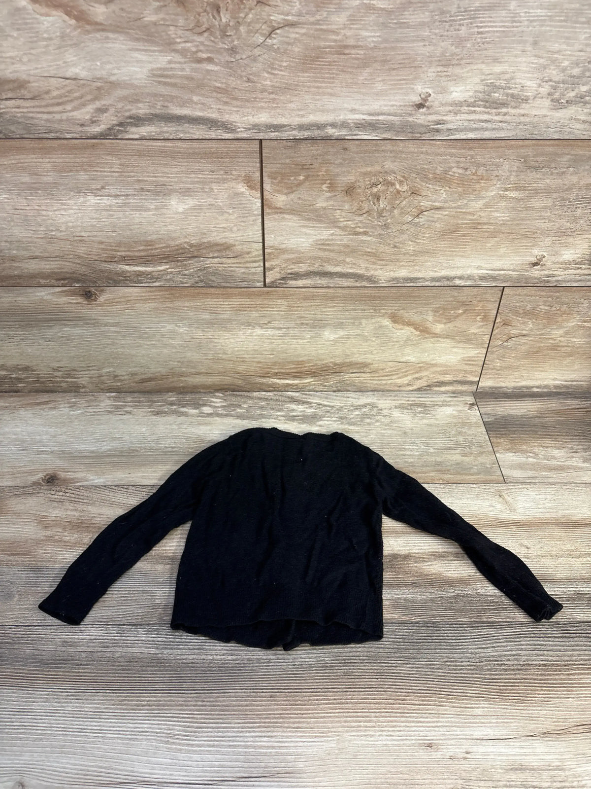 Back view of Cat & Jack knit cardigan showcasing long sleeves and black knit fabric with a wood-look background