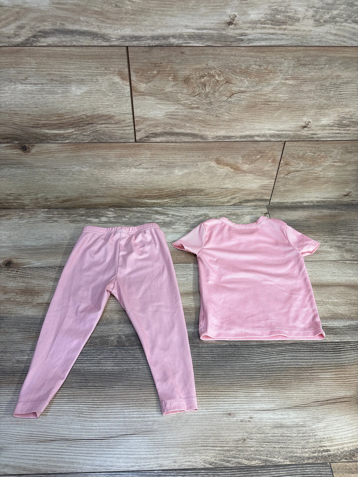 Flat lay of Shein pink 2-piece ribbed pajama set with short-sleeve top and long pants on wood flooring